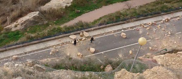 Dos personas caminan entre las rocas desprendidas, una zona cortada